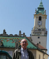 Me standing in front of building with green shingled roof and clock tower