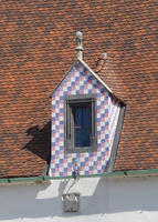 Roof with pastel red white and blue tiles surrounding windows