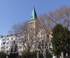 Statuary and trees in front of building with green spire