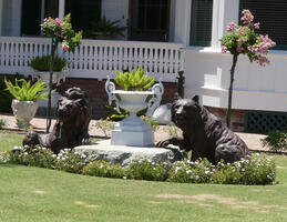 Sculptures of lion and bear (or wolf) surrounded by small flowering shrubs and small trees at each side