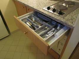 Open utensil drawer in kitchen showing knives, forks, and spoons