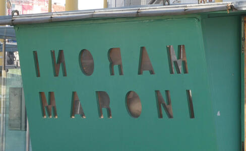 Kiosk with word MARONI mirror-reversed above the word MARONI (chestnuts)