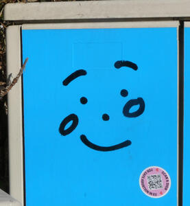 smiling face graffitti on blue utility box