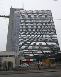 Multi-story building with mirrored glass that is arranged in a wavy pattern.