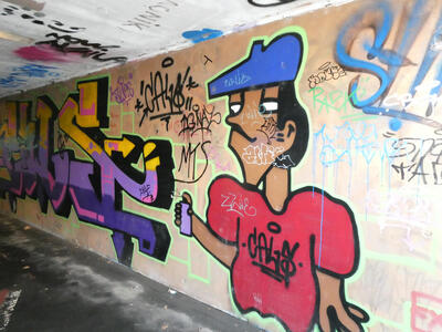 Graffiti art of a man in a beret spray-painting a wall