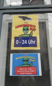 store signs with green alien as mascot