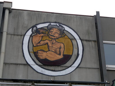 Shirtless man with “Popeye Arms” drinking from a glass.