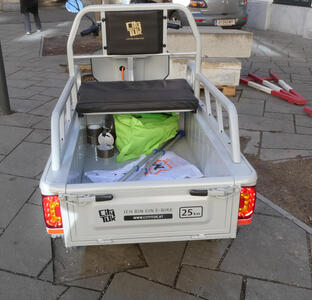 Rear view of small electric truck; on back it says “Ich bin ein E-bike 25 km”