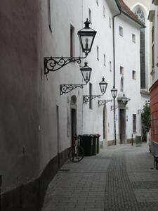 View down curving street, lamps on buildings.