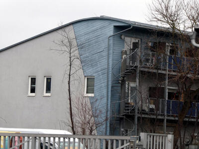 Apartment building with curved roof and wedge-shaped blue wood siding