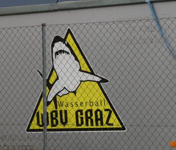 Yellow triangular logo with a shark and words Wasserball WBV Graz