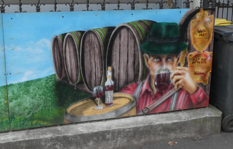 Painting of man drinking beer; behind him are four beer barrels. He is wearing a green Tyrolean-style hat