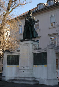 Statue of man in military garb drawing a sword