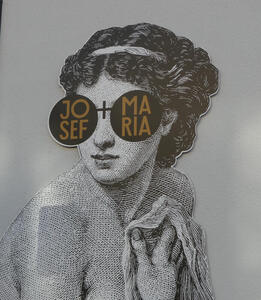 Woman with curly hair wearing glasses labeled Josef + Maria