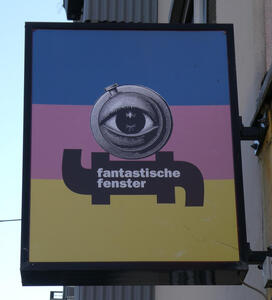 Sign for „fantastische fenster“ with a large eye on a striped background