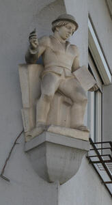 Sculpture of young boy holding a piece of chalk and a slate.