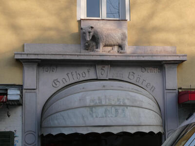 Sculpture of bear above lintel; on storefront, „Gasthof Bären“