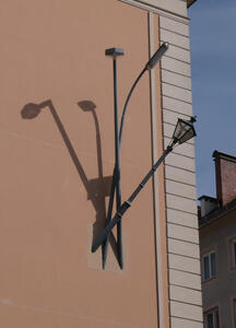 Three lamp posts, old-fashioned, fluorescent, and LED, attached to a wall.