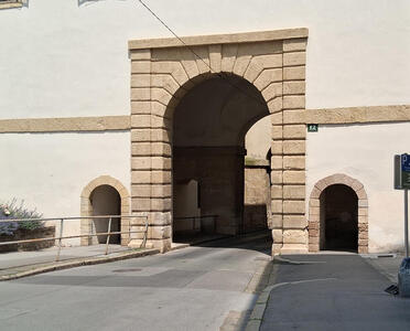 Plain wall with large arch for vehicles; small arches at both sides for pedestrians