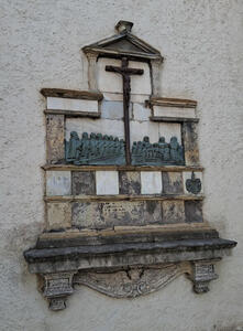 Reliefwork of people praying at a cross.