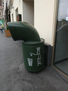 Garbage can with cartoon of stick figure person dropping garbage into a wire can.