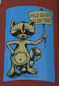 Raccoon holding a sign: „Pelz gehört den Tieren!“