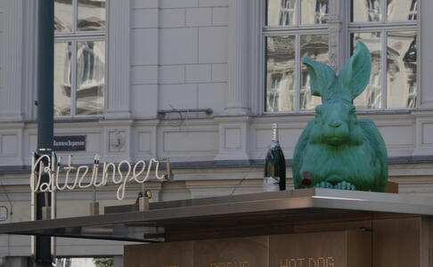 Sculpture of large green rabbit next to a bottle; this is on the roof of a snack shop