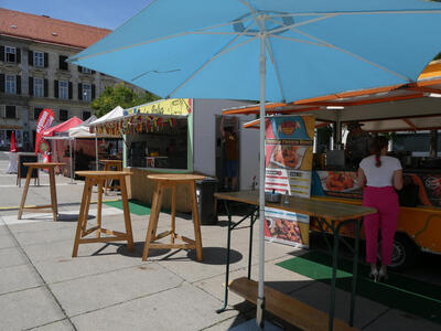 Blue umbrella in front of food stand.