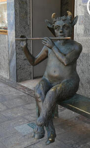 statue of pan seated playing flute