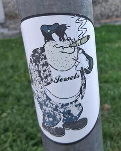 Cartoon dog with fat jowls, smoking a cigar. His T-shirt reads Jewels