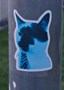 Sticker of a cat with black spots on its face. The cat is wearing a tie.
