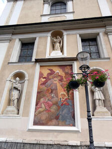 Painting of God shining light down on Mary; painting is surrounded by religious statuary