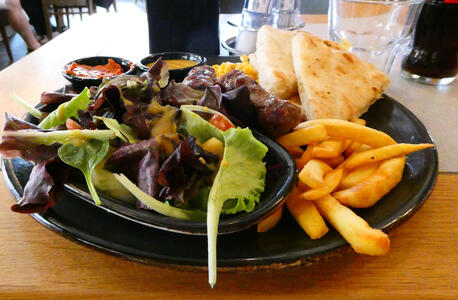 Meal with salad, fries, cevapcici, corn, and flatbread