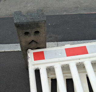 Traffic barrier on its side. The brick looks like a sad face.