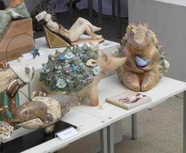 Ceramics in shape of fish, hedgehogs, and woman reclining on a chaise longue