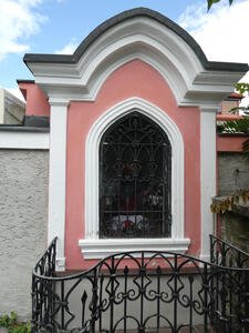 Small pink-painted shrine; in the shrine are flowers and an extinguished candle