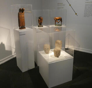 Small wooden and stone sculptures of people, people’s heads, and animals.