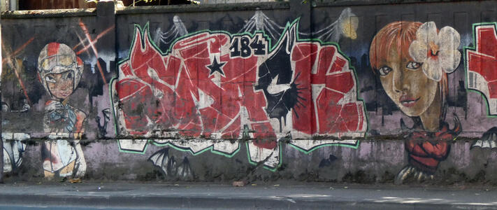 At left, person in racing helmet. Grafitti in middle. At right, woman with flower in her hair