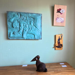 Blue relief of a worker hanging on wall; on table, a bird-like sculpture