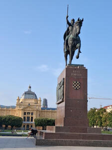 Statue of man on horseback in foreground, large yellow building with dome in background