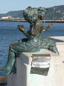 Bronze sculpture of two seated women, facing away from each other. A newspaper (part of the sculpture) is near them.
