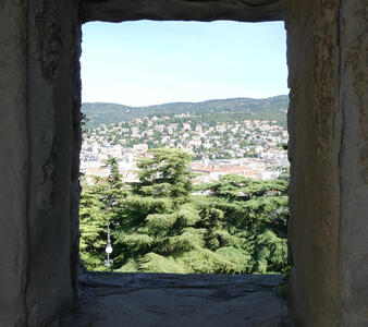 View of Trieste buildings on hills as seen through an opening in the battlements