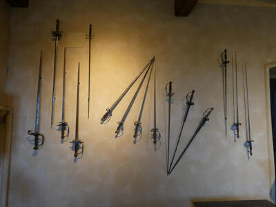 Array of swords on wall; they are facing at various angles