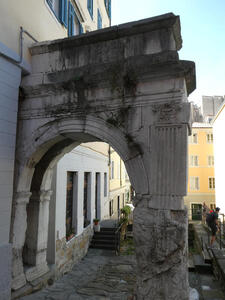 Portion of a first-century stone arch. The upper part is attached to a modern building.