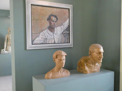 Painting of Rovan on wall; beneath it, the bust of him as a young man, and to its right, the bust of an older man with a moustache