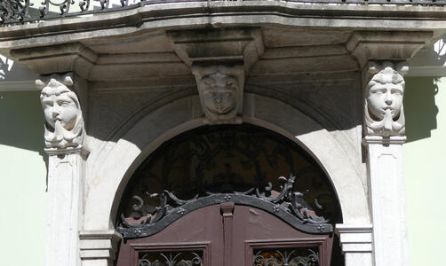 Two stone faces at side of an arched doorway