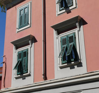 Windows with green wooden shutters. The shutters are slightly askew.