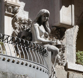 Stone sculpture of woman seated on edge of balcony