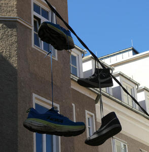 Two pairs of shoes hanging over a line.