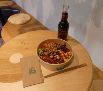 Table with poke bowl, napkin, chopsticks, and bottle of soda